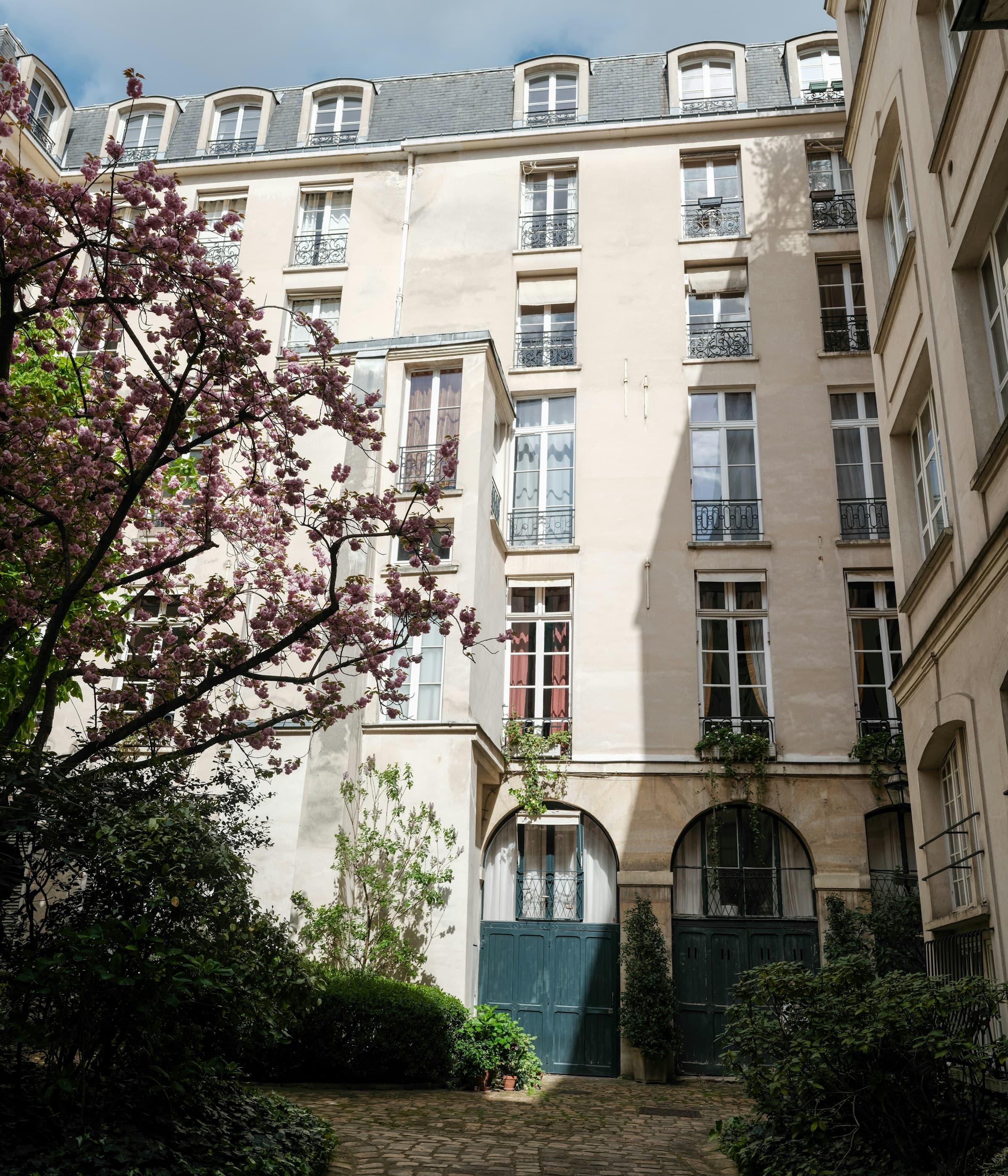 Cour intérieure d’un immeuble ancien avec un arbre en fleurs, à La Tour-de-Peilz